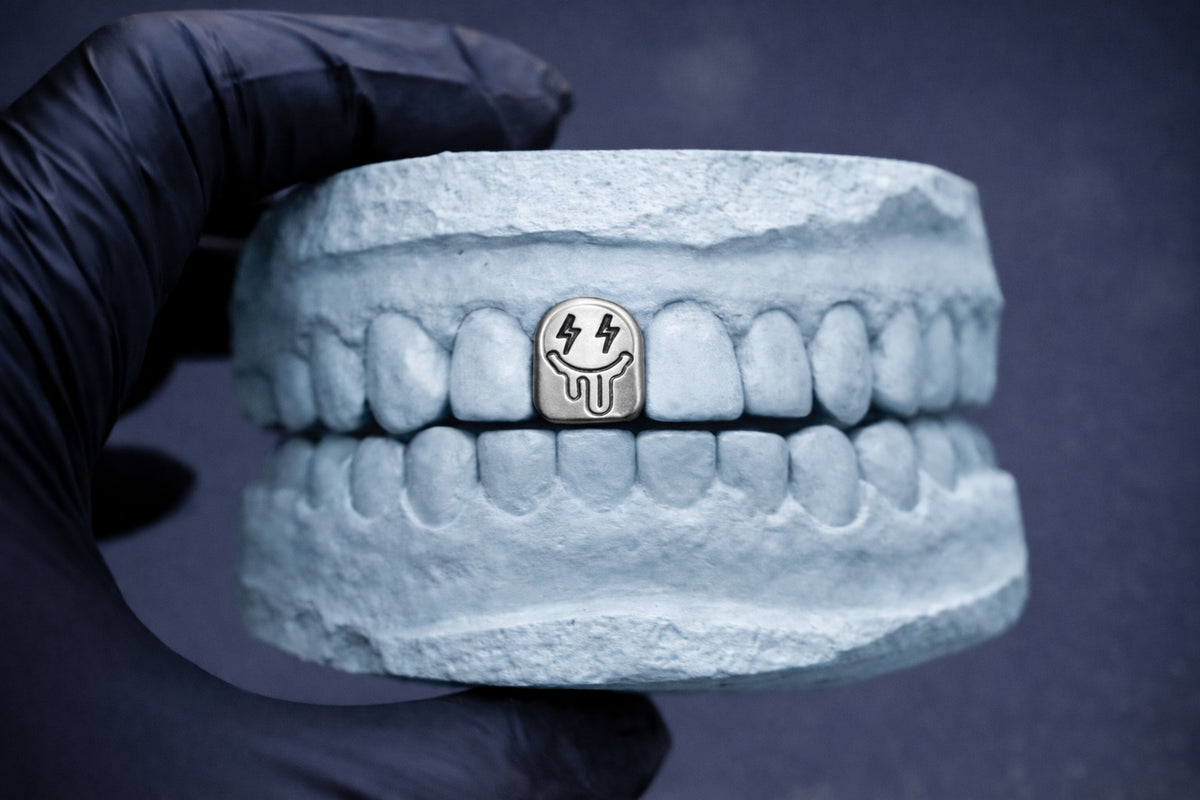 3D-printed dentures with a small metallic object on a dark background