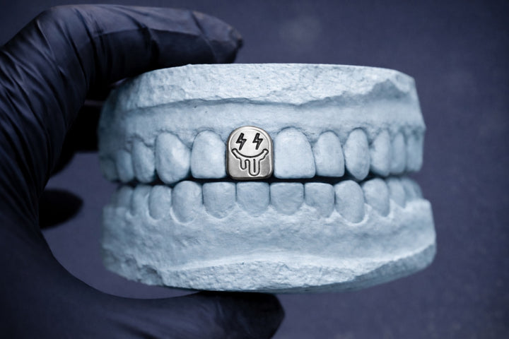 3D-printed dentures with a small metallic object on a dark background